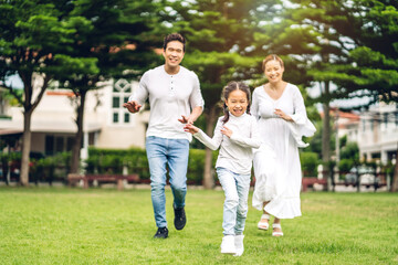 Naklejka na ściany i meble Portrait of enjoy happy love asian family father and mother with little asian girl smiling running playing and having fun moments good time in summer park at home