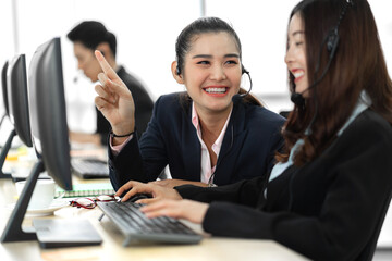 Group of happy asian smiling call center business operator customer support team phone services agen working and talking with headset on desktop computer at call center