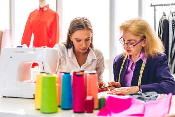 Portrait of woman fashion designer stylish sitting and working with color samples.Attractive woman working with mannequins standing and colorful fabrics at fashion studio