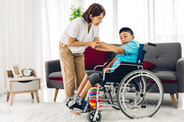 Naklejka premium Portrait of asian physiotherapist carer helping and playing with special disabled child health problem by doing exercises sitting in wheelchair in rehabilitation clinic.disability care concept