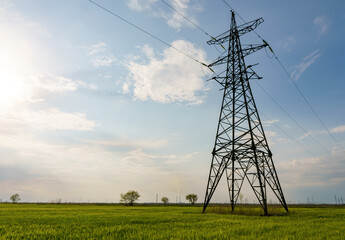 High voltage lines and power pylons and a green agricultural landscape on a sunny day.