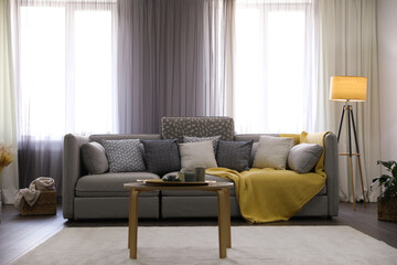 Elegant living room with comfortable sofa near windows. Interior design