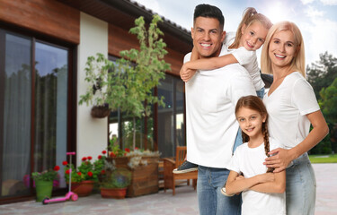 Happy family standing in front of their house on sunny day