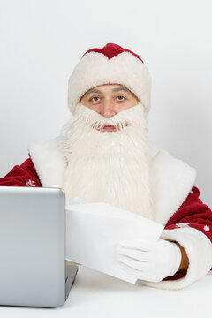 Santa Claus is sitting at his desk and reading letters.