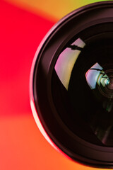 The camera lens and the beautiful light orange color. The orange rays of refraction on the lens. Optics. Vertical photo