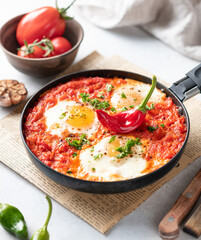 Shakshuka, fried eggs with vegetables in a frying pan, traditional israeli cuisine