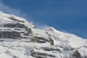 Bergmassiv im Schnee mit Verwehungen und blauer Himmel