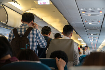 Fototapeta na wymiar People are standing in an airplane cabin before disembarking