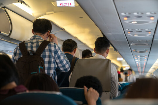People are standing in an airplane cabin before disembarking