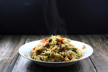 Fried and stirred spicy instant noodle with crab stick, fresh mussel meat, baby corn, chilly and basil on the plate. Famous traditional street food menu in Asia.