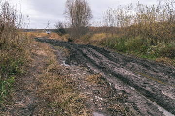 An impassable road, off-road track in autumn forest. Deep ruts in the slushy autumn road