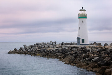 Lighthouse on rock Jetty in the ocean at dusk with light on