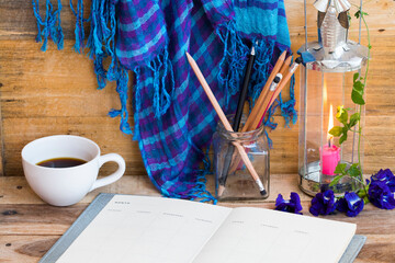 notebook planner for business work with hot coffee ,blue scarf ,lamplight and flowers of lifestyle...