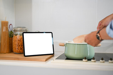 Cropped of man using digital tablet for recipes cooking in a modern kitchen.