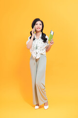 Image of smiling woman holding passport with ticket and mobile phone isolated over yellow background