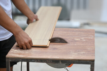 Closeup of a carpenter hands working with equipment on wooden workbench.