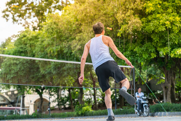 Asia middle-aged man playing shuttle cock at park. Outdoor sport