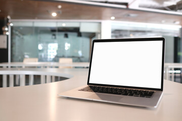 Mock up blank screen laptop with white screen on wooden desk in moern room.