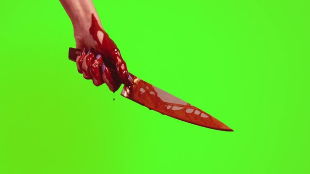 Blood runs down the knife and hand on a green background. The killer's hand holds a knife in bright blood.