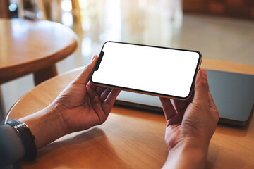 Mockup image of a woman holding mobile phone with blank white desktop screen