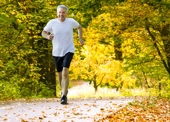 Active mature man running in autumn park