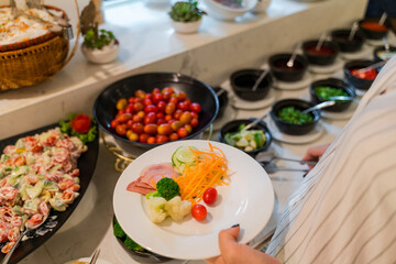 Woman hand taking food in buffet