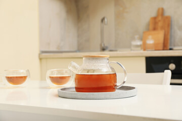 Glasses and pot of tea against kitchen interior