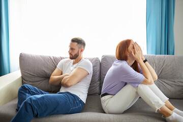 young caucasian couple offended on each other, sit turning away from each other, redhead female and...