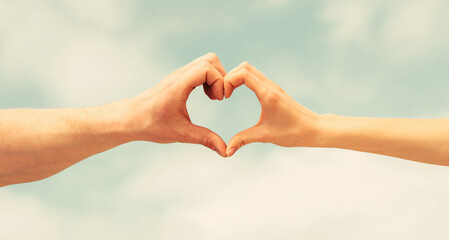 Female and man hands in the form of heart against the sky. Hands in shape of love heart. Heart from...