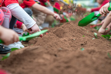 Closeup group of Asian school kids learn to plant tree seeds on sand outdoor