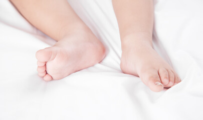 Legs of little baby lying on bed.