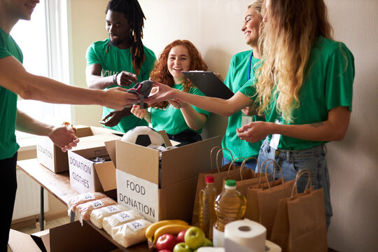 active young people enjoys volunteering at food and clothes bank, voluntary company. diverse people working in voluntary company with friends putting food for donation into boxes