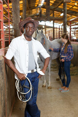 Portrait of mature afro man horse farm worker standing at stable