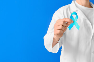 Doctor with blue ribbon on color background. Diabetes awareness concept