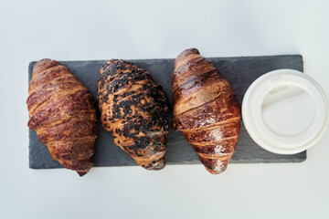 Red cup with coffee and a croissant on a table in a cafe. Morning breakfast. High-quality photo