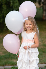 Fototapeta na wymiar Portrait of little girl in white dress with balloons on the street