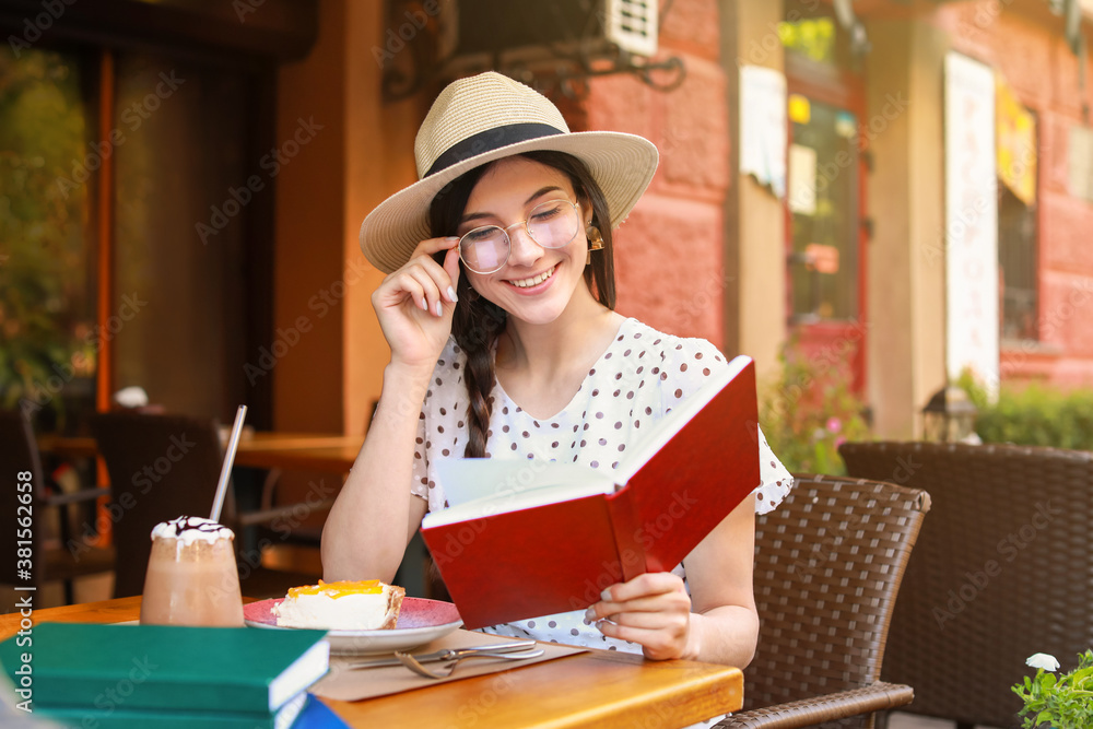 Poster beautiful young woman reading book in street cafe