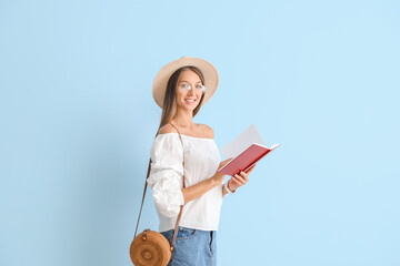 Beautiful young woman with book on color background