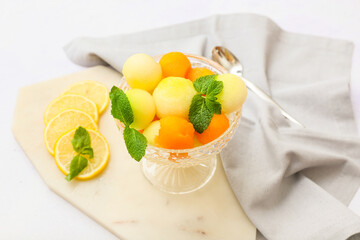 Bowl with tasty melon balls on white background