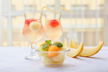 Tasty melon balls with cold cocktail on table