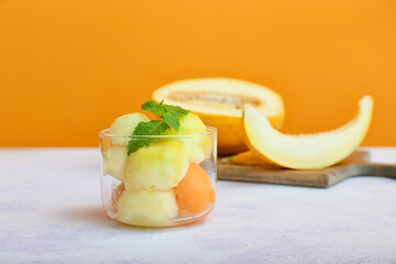 Glass with tasty melon balls on table