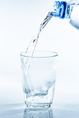ペットボトルから透明なガラスのコップに注がれる水