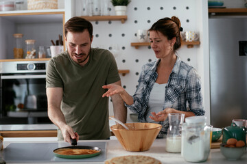 Young couple making pancakes at home. Loving couple having fun while cooking