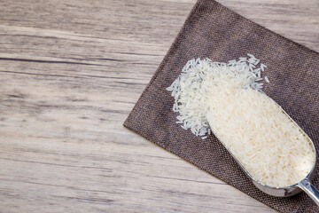 The rice on spoon put on the rice sack. White rice or Thai Jasmine rice in wooden bowl on wood table background.