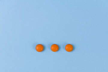 three orange pills on a blue background