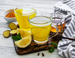 Energy tonic drink with turmeric, ginger, lemon and honey on a white wooden background