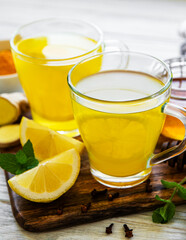 Energy tonic drink with turmeric, ginger, lemon and honey on a white wooden background