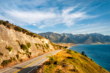 Picturesque perspective view of Highway 6 on the side of Lake Hawea with mountain peaks in the distance in Otago Region, New Zealand, Southern Alps.
