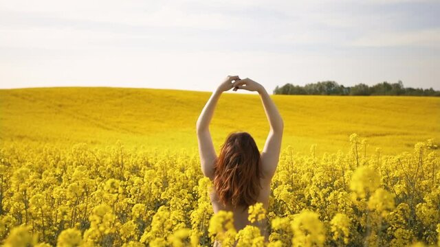 Young naturist woman enjoys Spring in rapeseed field