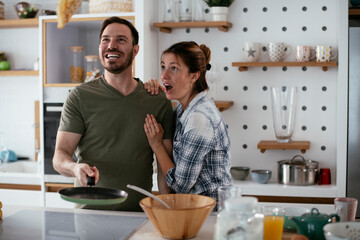 Young couple making pancakes at home. Loving couple having fun while cooking